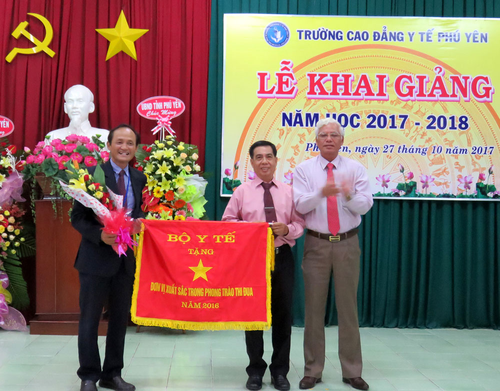 Phó Bí thư thường trực Tỉnh ủy Lương Minh Sơn trao cờ thi đua xuất sắc cho lãnh đạo nhà trường - Ảnh: MẠNH THÚY